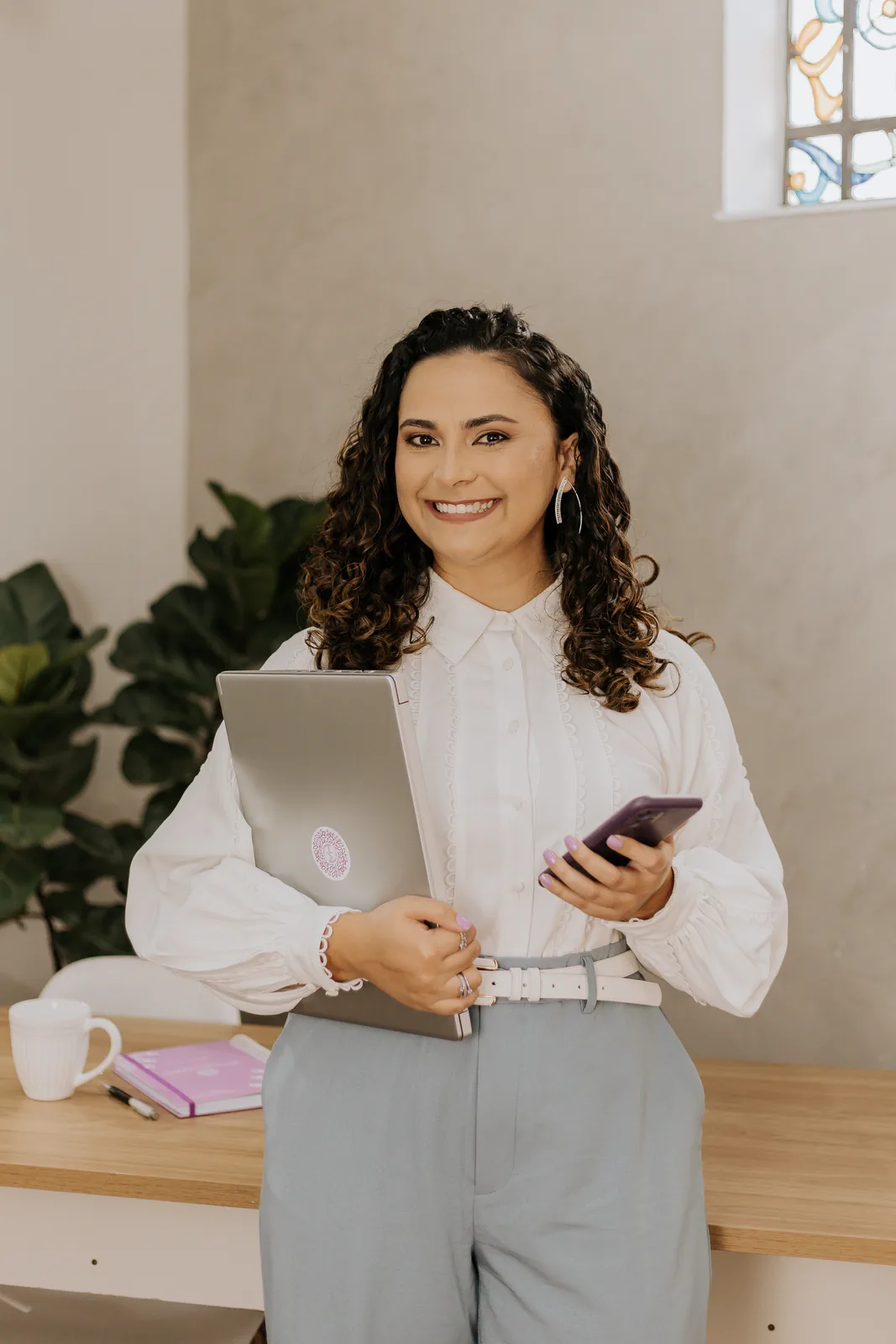 Josi Miranda com notebook e celular para atendimento psicológico online
